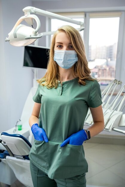 Portrait of friendly happy female dentist in uniform and waiting patient at modern clinic