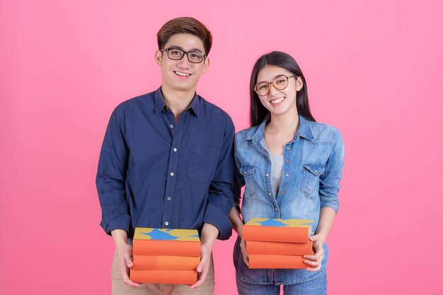 Portrait friendly teenage man and woman wearing eyeglasses holding books and smiling with funny education teenage concept