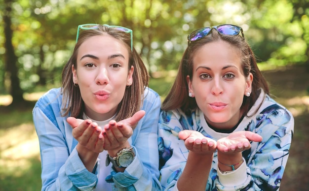 Photo portrait of friends blowing kiss at park