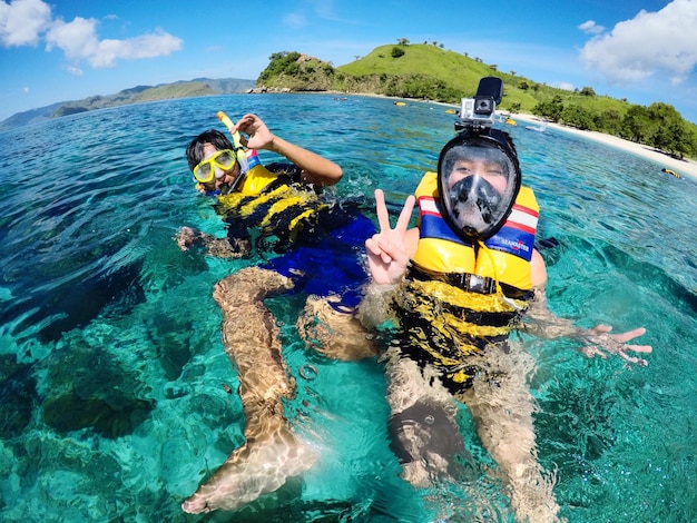 Foto ritratto di amici che fanno gesti mentre fanno snorkeling in mare