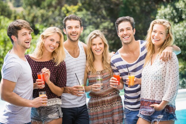 Portrait of friends having juice near pool