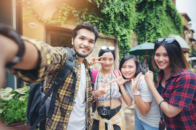 Portrait of friends taking selfie while standing outdoors