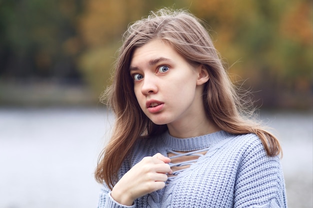 Portrait of frightened scared woman, surprised teenager girl outdoors in a park