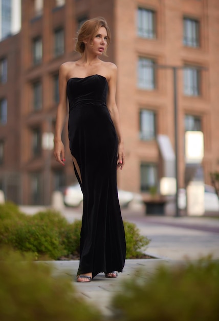 Portrait from back of elegant girl with long curly hair walking on steer on old building background