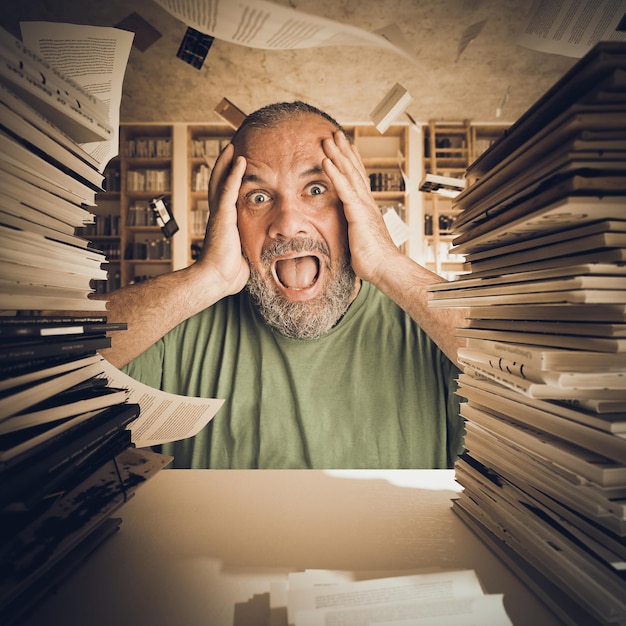 Photo portrait of frustrated man with books stack on table