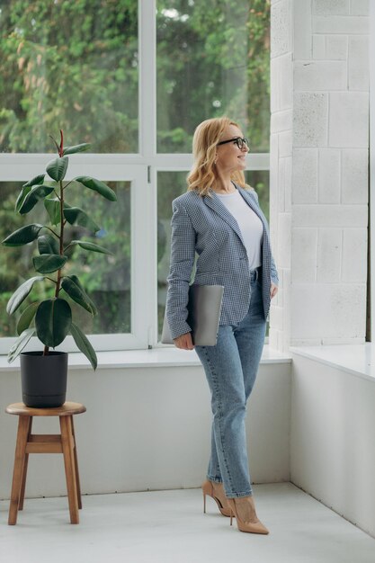 Portrait of fulllength mature woman holding laptop in hands businesswoman 50s