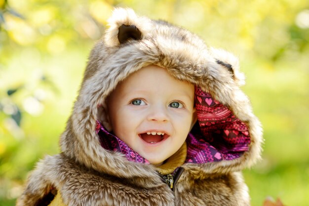 Portrait of funny baby boy wearing fur jacket outdoors