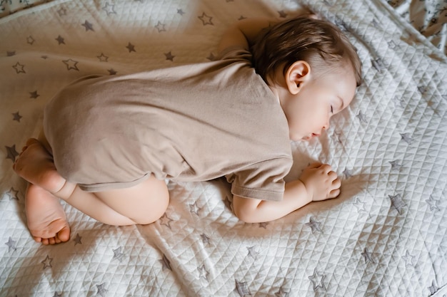 Portrait of a funny baby sleeping on his stomach on the bed at home Close up