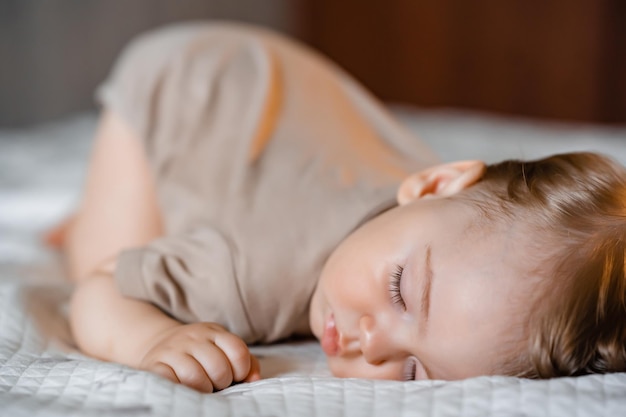 Ritratto di un bambino divertente che dorme a pancia in giù sul letto di casa primo piano