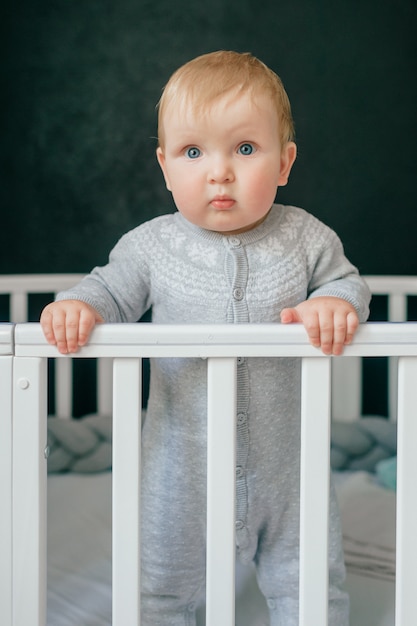 Portrait of funny baby standing in crib