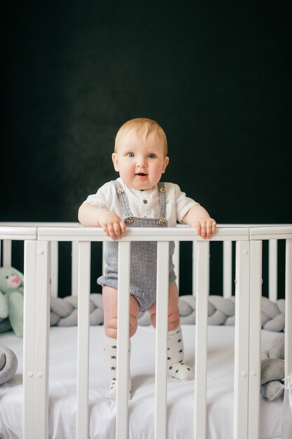 Portrait of funny baby standing in crib.