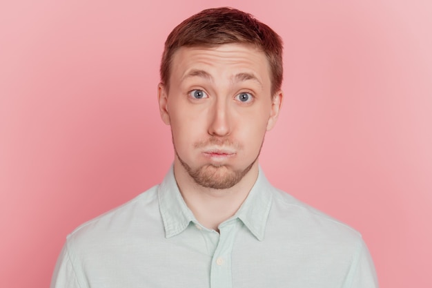 Photo portrait of funny chidlish crazy guy inflate cheeks look camera on pink background