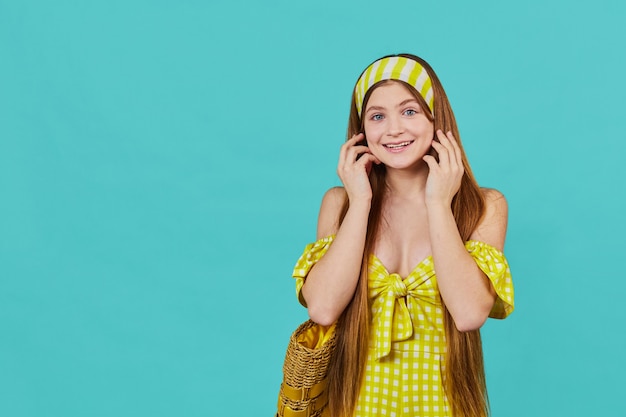 Portrait of funny emotional young girl on blue wall. Pretty surprised lady in yellow dress posing. Summer vacation concept.