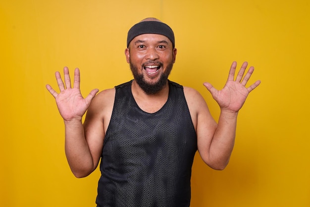 Portrait of funny excited bearded fat man in sportwear on yellow background