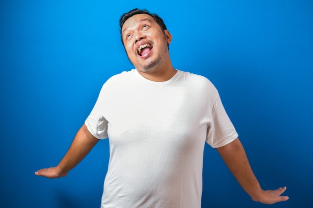 portrait of a funny fat asian man in white tshirt smiling and dancing happily