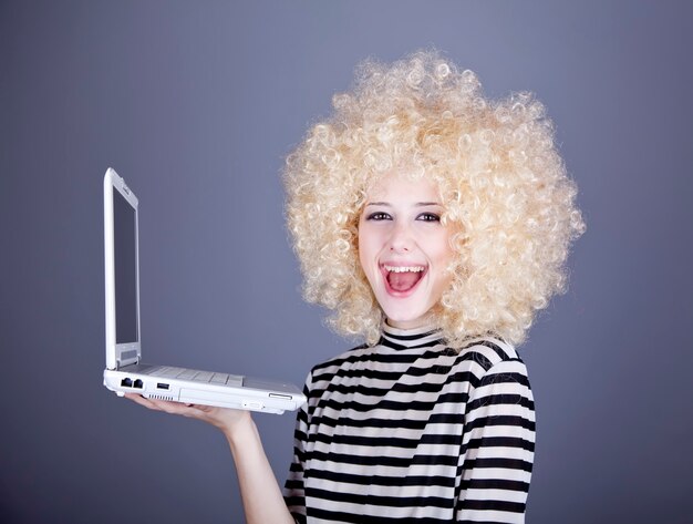 Portrait of funny girl in blonde wig with laptop.