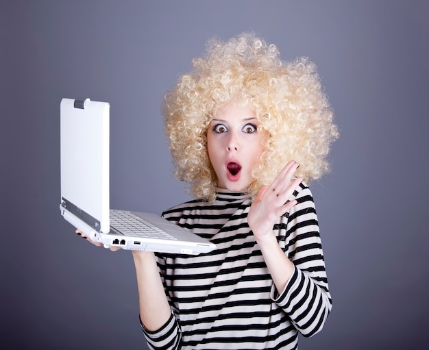 Portrait of funny girl in blonde wig with laptop.