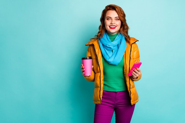 portrait of funny lady hold hot coffee mug beverage browsing telephone walk street wear casual yellow overcoat scarf pants pullover.