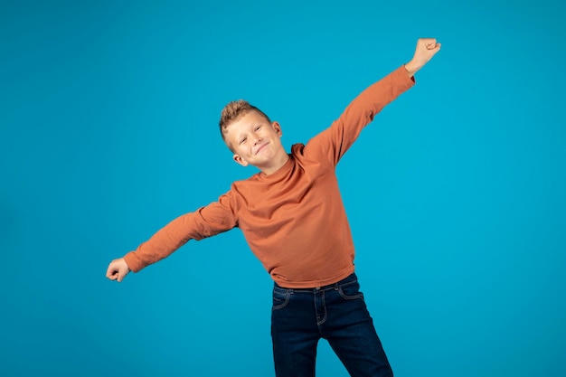 Portrait of funny little boy spreading arms and pretending flying