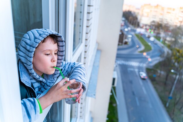 バルコニーからシャボン玉を吹く面白い素敵な小さな男の子の肖像画。家で遊んでいる子供。