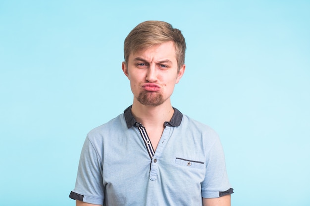 Photo portrait of a funny man offended cute, wearing a blue polo t-shirt on blue