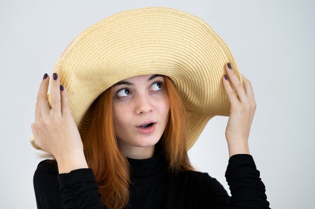 Portrait of funny redhead woman in bag yellow straw hat.