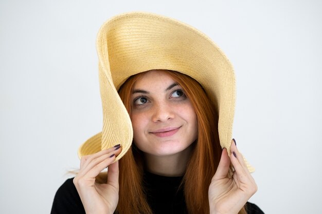 Ritratto di donna rossa divertente in cappello di paglia giallo