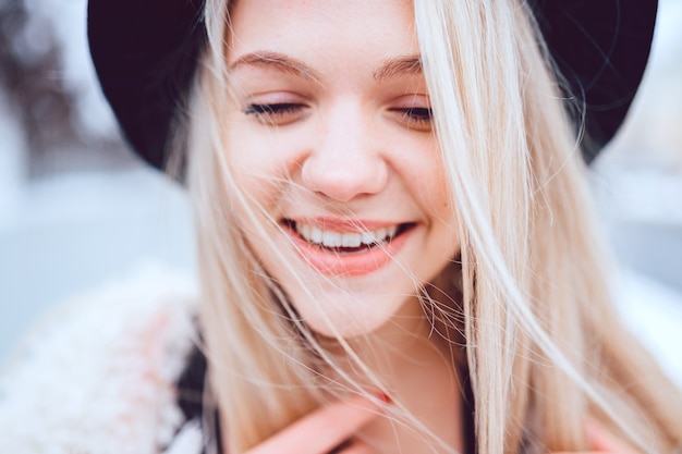 Ritratto di ragazza bionda alla moda sorridente divertente in cappello