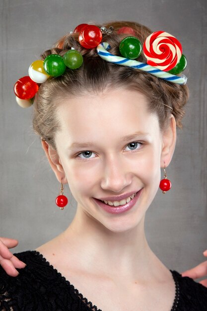 Portrait of a funny teenage girl with a wreath of sweets on her head.