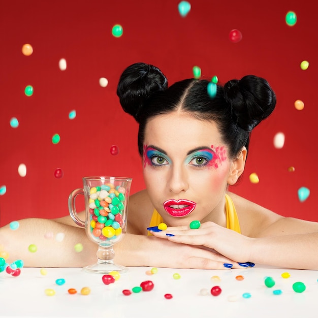 Portrait of funny woman with colorful makeup under the falling candy drops