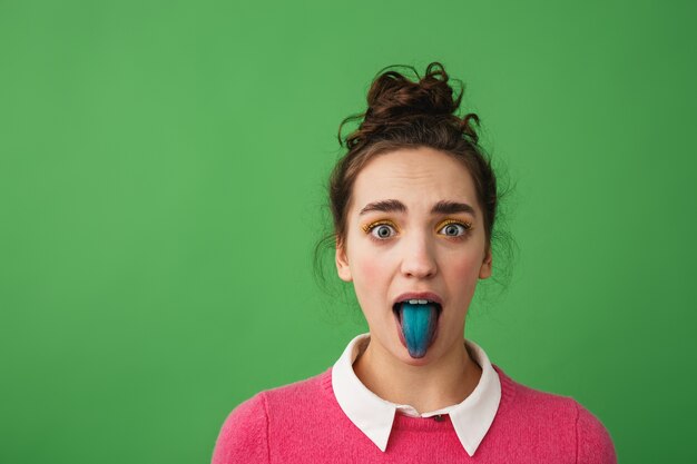 Photo portrait of a funny young girl standing isolated, showing blue tongue