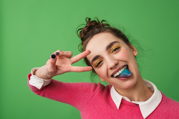 Portrait of a funny young girl standing isolated, showing blue tongue