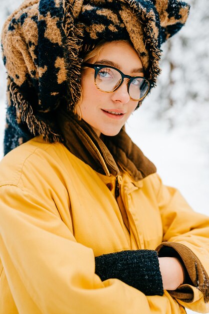 Portrait of funny young hipster girl in glasses with the turban of the scarf posing in the forest