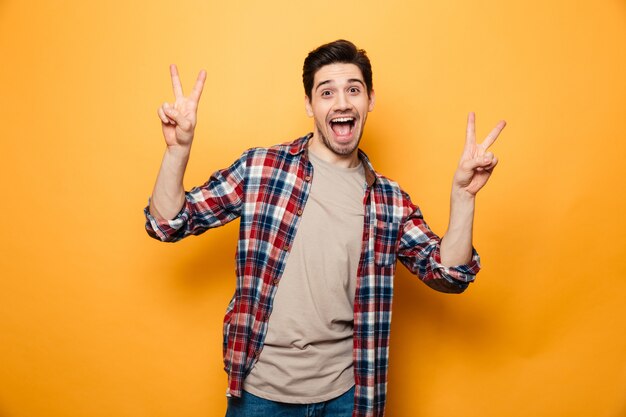 Portrait of a funny young man showing peace gesture