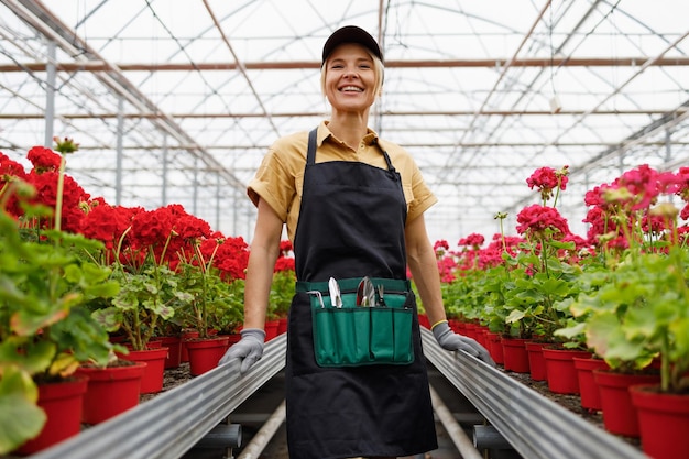 ベルトに花の栽培の道具をつけた花の温室の庭師の女性の肖像画