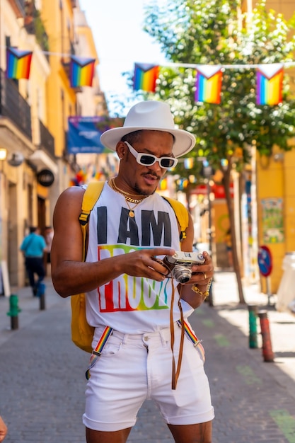 Portrait of a gay black ethnicity man at the pride party looking at the photos on the camera LGBT flag