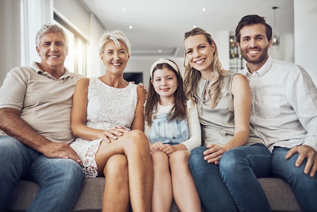 Portrait generations and family on sofa smile and relax on break bonding together and in living room Face grandparents and mother with father daughter and on couch for quality time or happiness