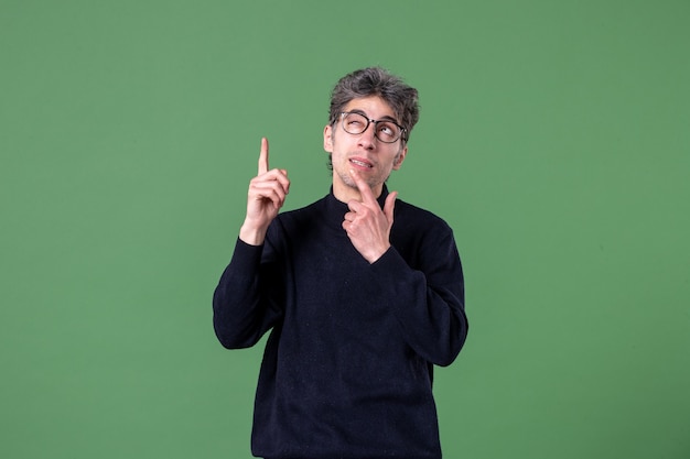 Portrait of genius man dressed casually in studio shot thinking green wall