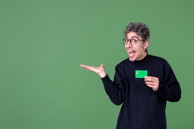 Portrait of genius man holding credit card in studio shot green wall