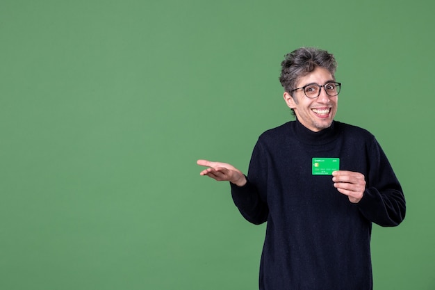 Portrait of genius man holding credit card in studio shot green wall