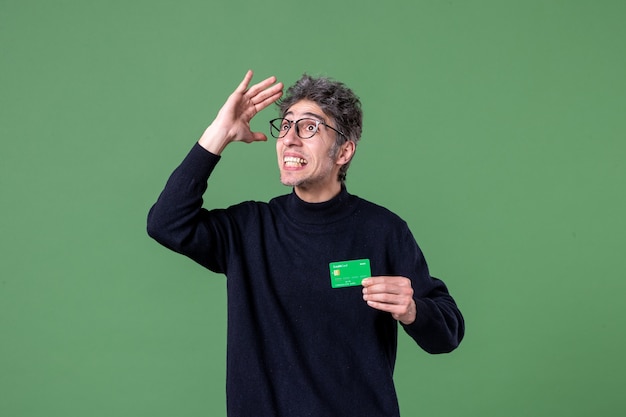 Portrait of genius man holding green credit card on green wall