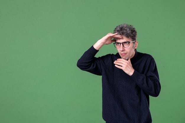 Portrait of genius man in studio shot looking at distance on green wall