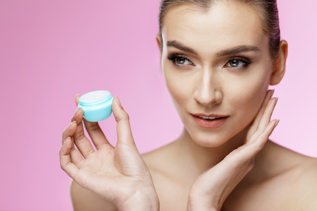 Portrait of a girl applying cream on her face