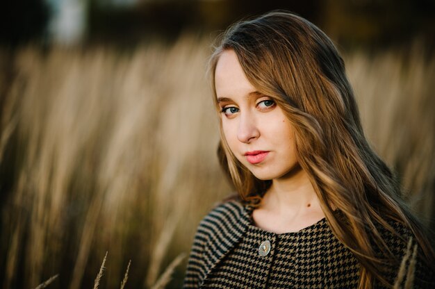 Portrait of a girl in autumn against the background of the field on nature.