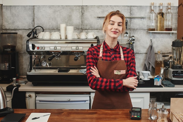 Portrait of a girl baristas at workplace on background of coffee