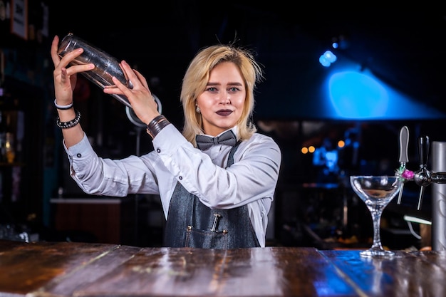 Portrait of girl barman surprises with its skill bar visitors while standing near the bar counter in bar