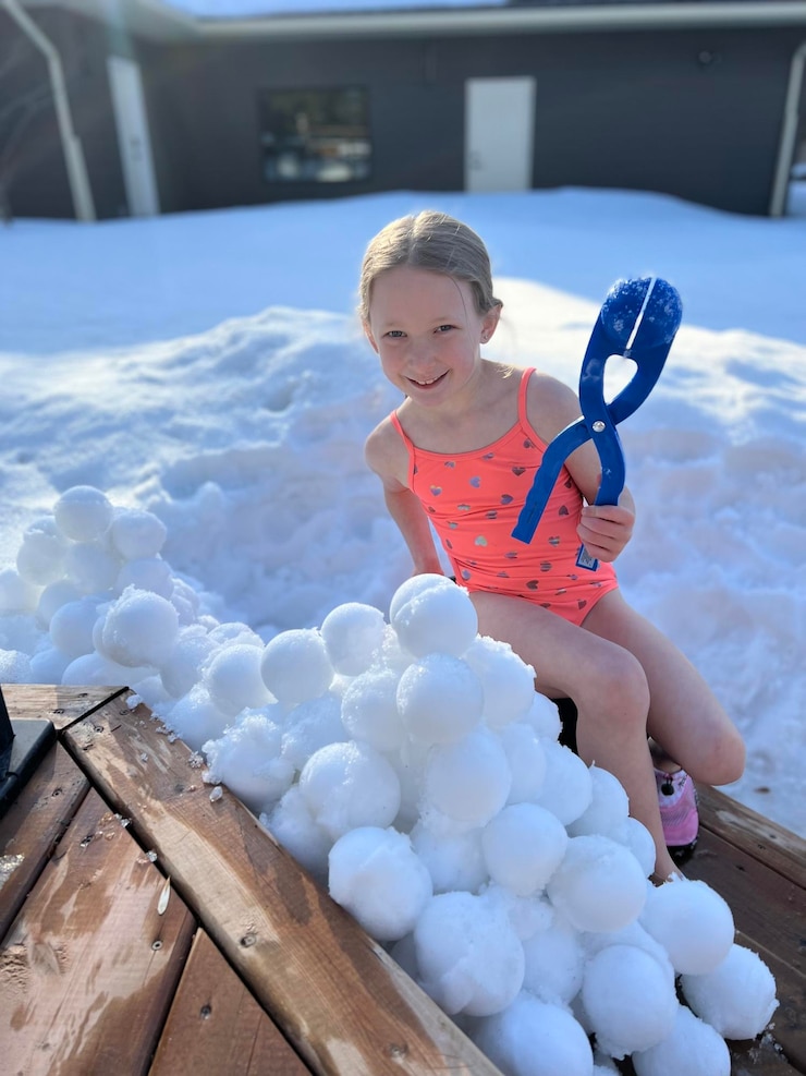 Photo portrait of a girl in in bathing suit playing in snow making snowballs