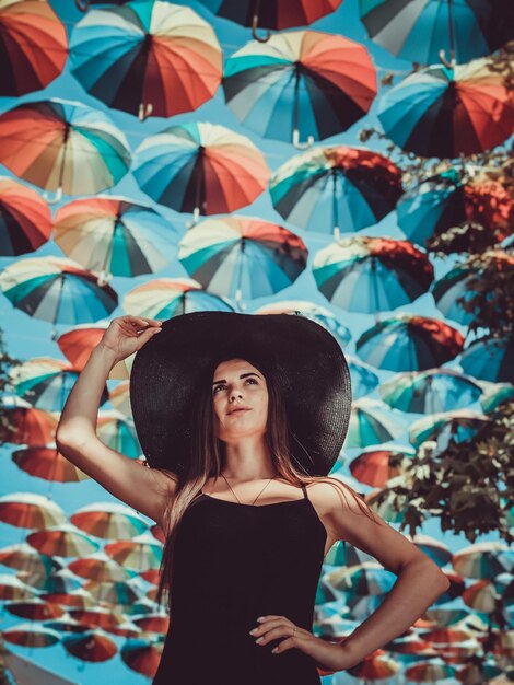 Foto ritratto di una ragazza in nero sotto gli ombrelli colorati