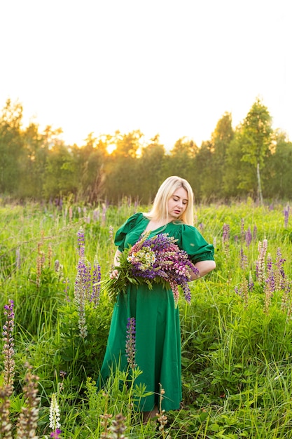 Portrait of a girl in a blooming field in the sun at sunset