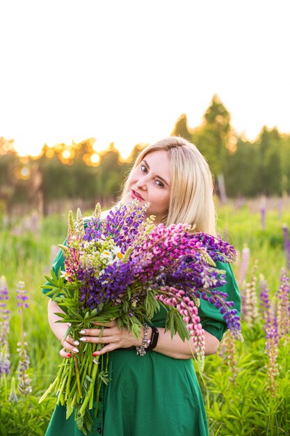 Portrait of a girl in a blooming field in the sun at sunset